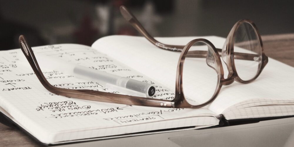 Glasses resting on a book with handwritten notes