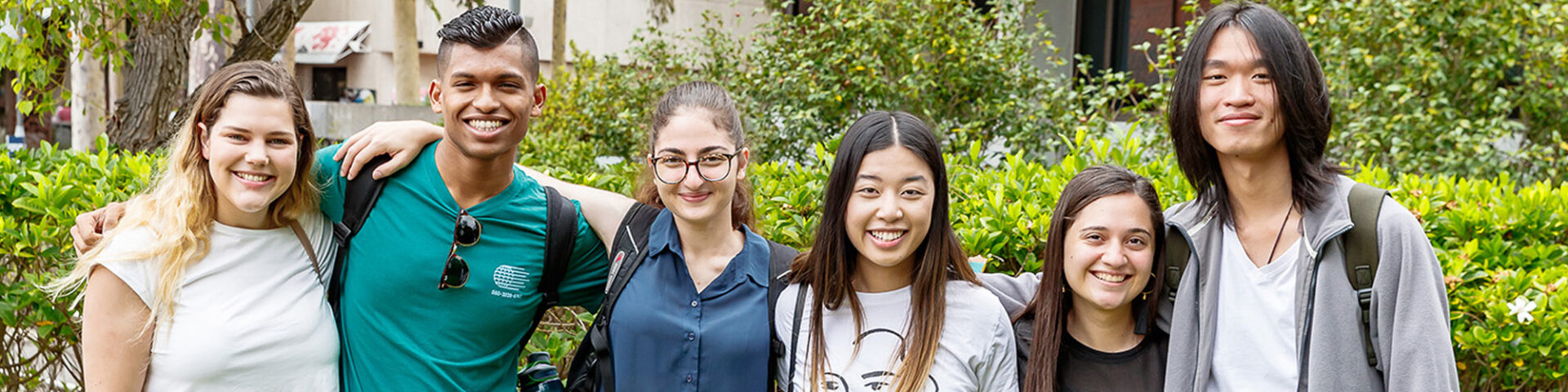 Multiple students standing next to each other with their arms around one another.