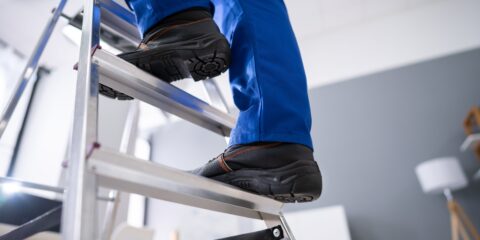 A person standing on two rungs on a ladder.