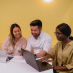 3 students sitting a desk with laptops