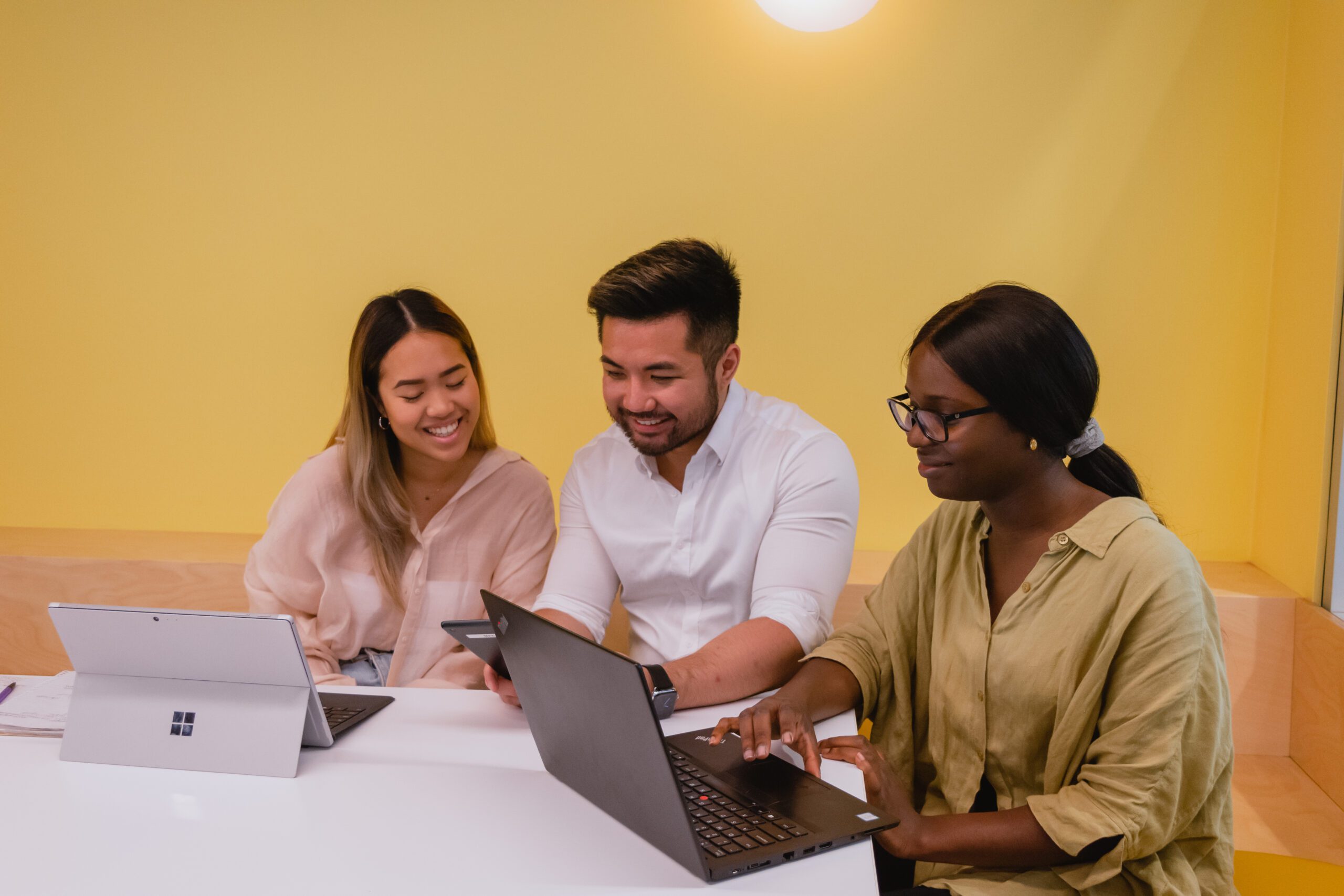 3 students sitting a desk with laptops