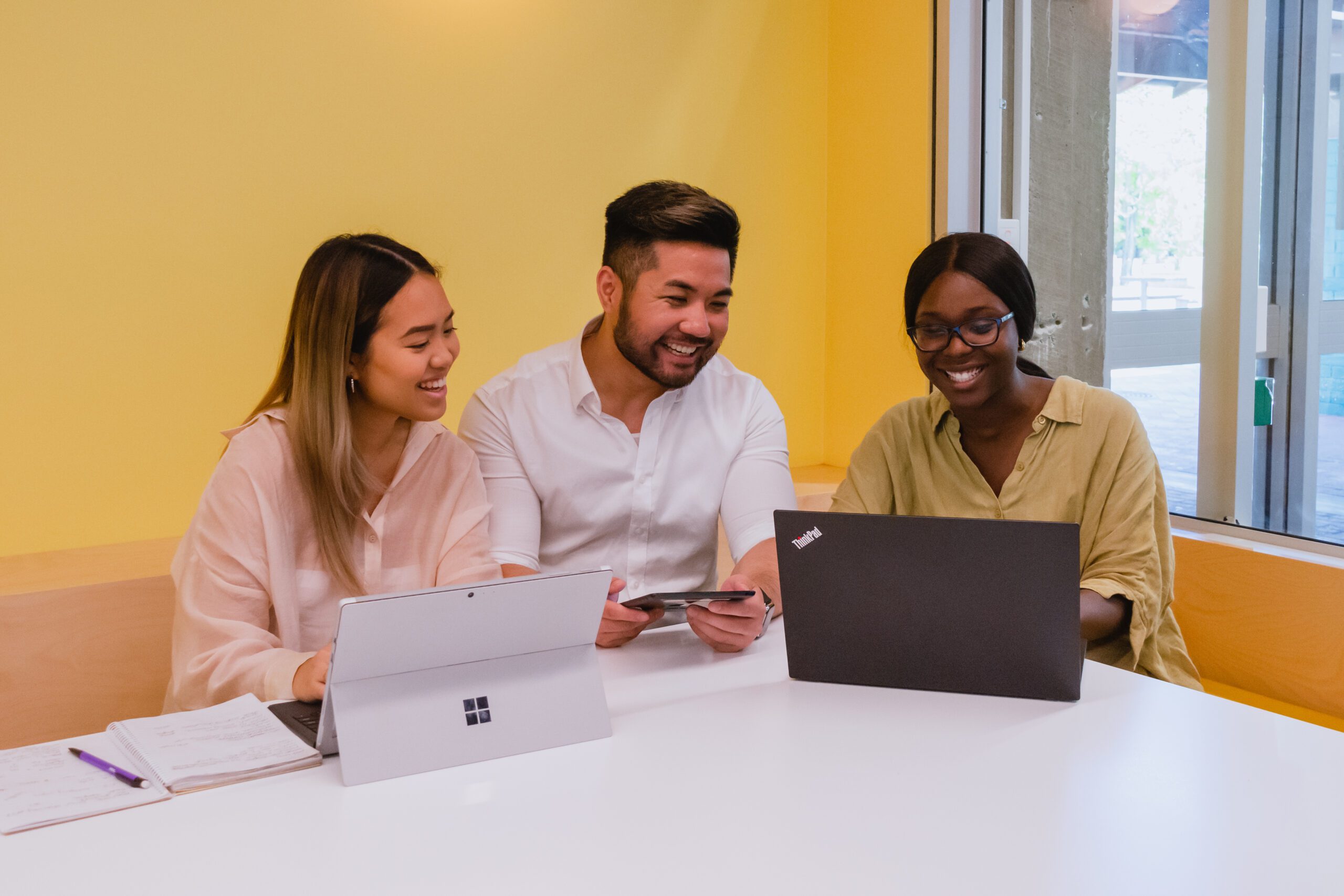 3 students sitting a desk with laptops