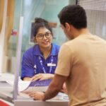A library staff member helps a student at the library help desk