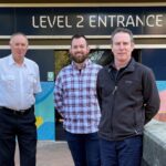 Cindy Carbutt, Chris Wright, James Robinson and Colin Sinclair from the Library Spaces Group stand in front of the level 2 entrance of the TL Robertson Library, smiling at the camera.
