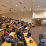 Students sitting in a lecture theatre looking at a presentation on the screen