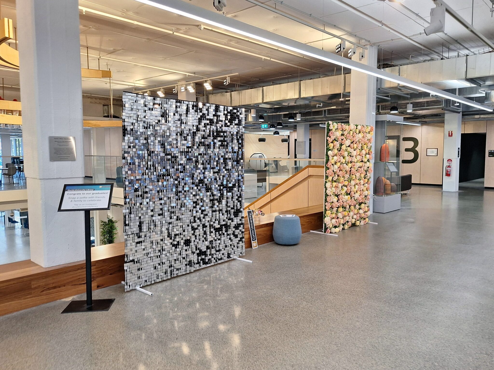 Photo taken in TL Robertson Library. It shows two photo backdrops located near a large set of stairs.