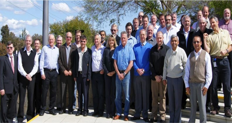 Curtin alumna Alex Atkins poses with colleagues in front of trees, smiling together as a group.