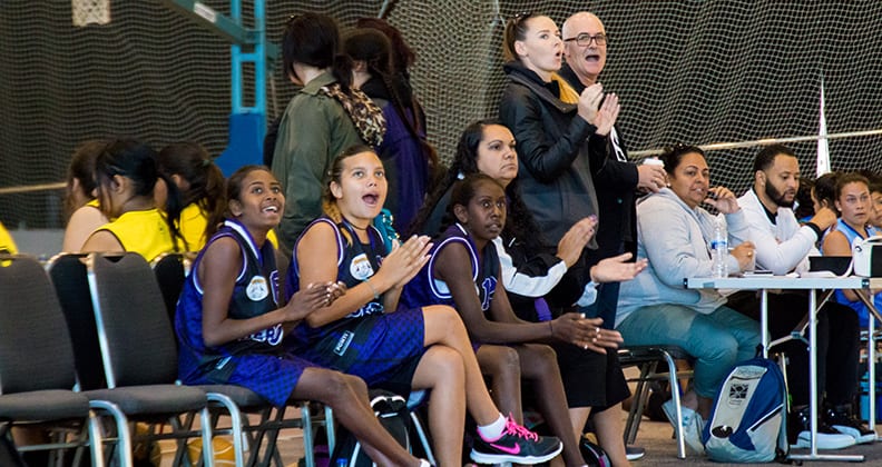 Spectators look on excitedly at basketball game.