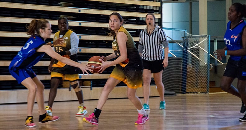 A competitor reaches to grab the ball from her opponent.