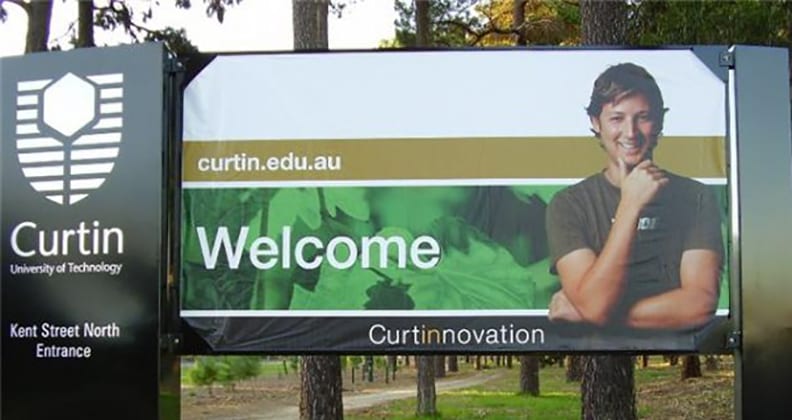 A younger Luke smiling from a Curtin billboard.