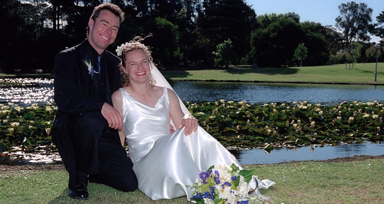 Martin and Tiffany on their wedding day in front of a grassy lake. 