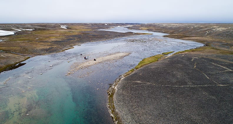 Crump and her team cross a wide, stone strewn river on Baffin Island.