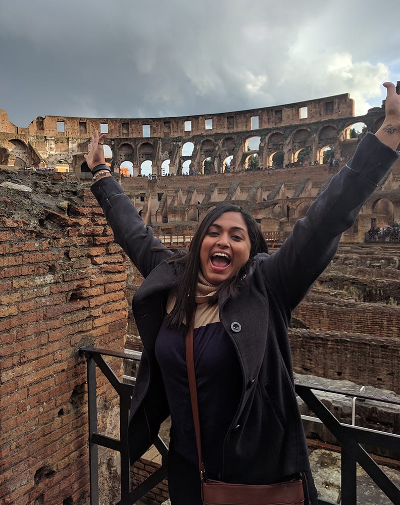 Swati with her hands in the air at the Colosseum in Rome.