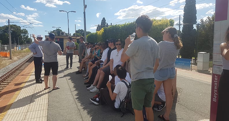 Group of young people stand on a station platform.