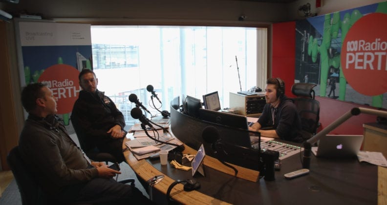 Bryans on the production desk at ABC Radio in Perth interviewing two sports professionals.