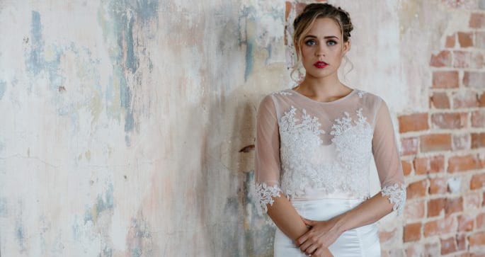 Woman wearing detailed lace wedding top with long satin skirt.
