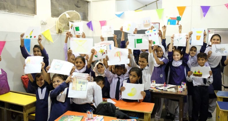 Girls from Anum School in Karachi, Pakistan, proudly display their artwork in a classroom. 