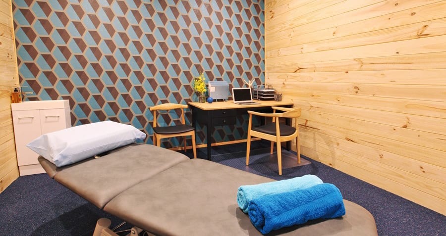 Massage bed, table and computer in clinic room.