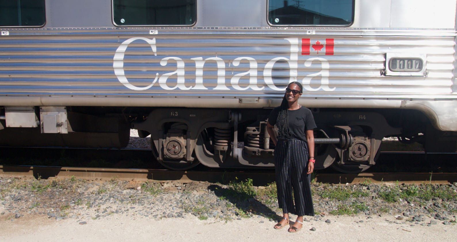 Abby Asomani stands in front a train with the words 'Canada' written on the side and the Canadian flag.