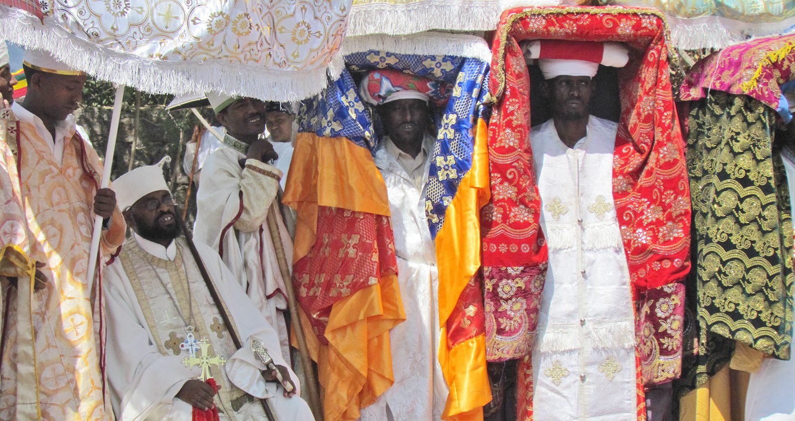 Priests from the Ethiopian Orthodox Church carrying wrapped tabots above their heads.