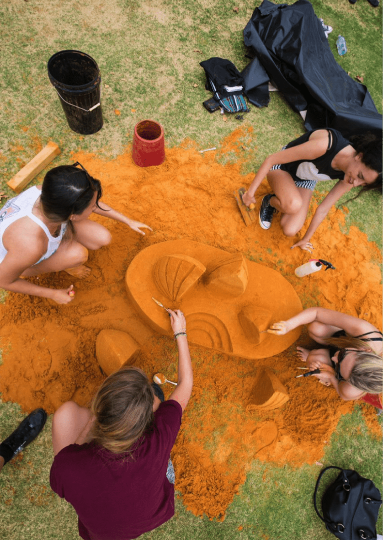 Students carving a sand sculpture of the Sydney Opera House
