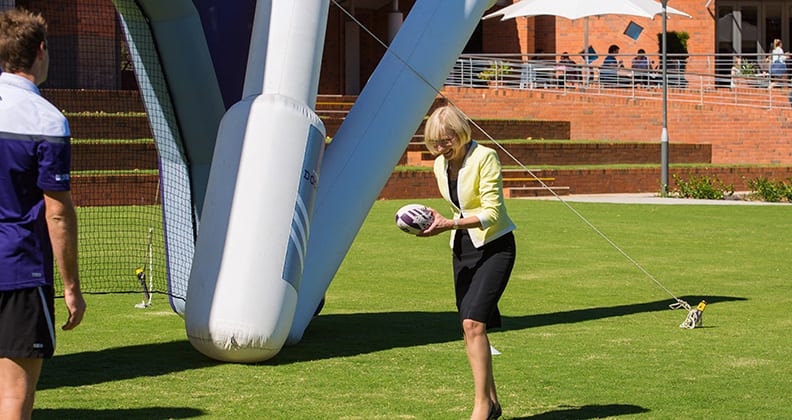 Vice-Chancellor Deborah Terry handballing to Fremantle Dockers player Michael Barlow