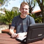 Student sitting outdoors with a laptop.