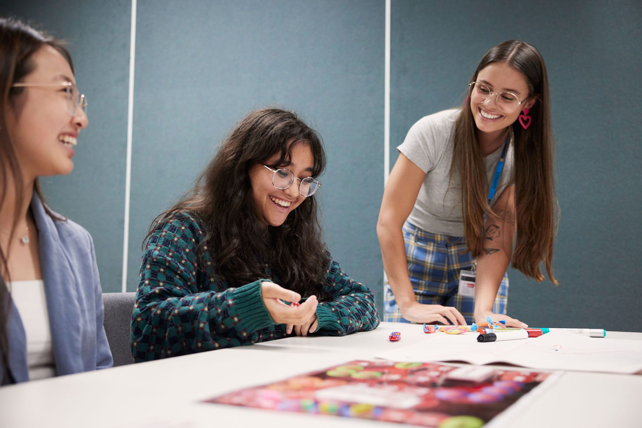 Students at a UniPASS session. Two students are sitting down at a table and the faciliator is standing nearby.
