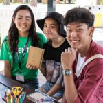 Three students sitting at a table outdoors