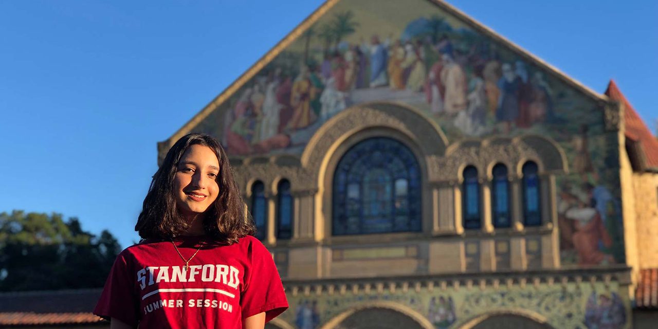 Student wearing a red Stanford t-shirt outside an historic building