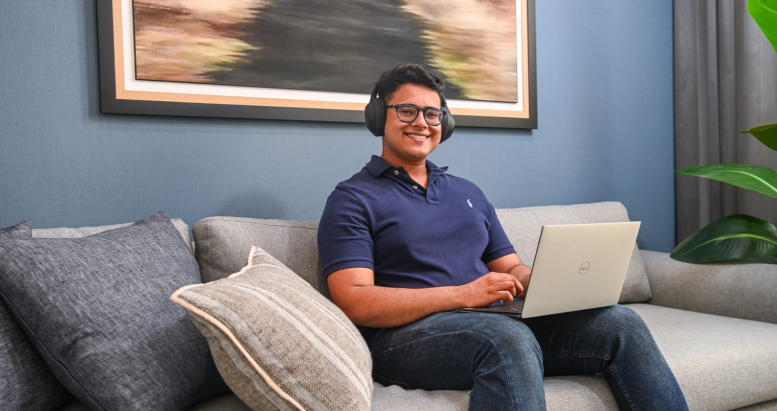 Student sitting on a sofa with a laptop.