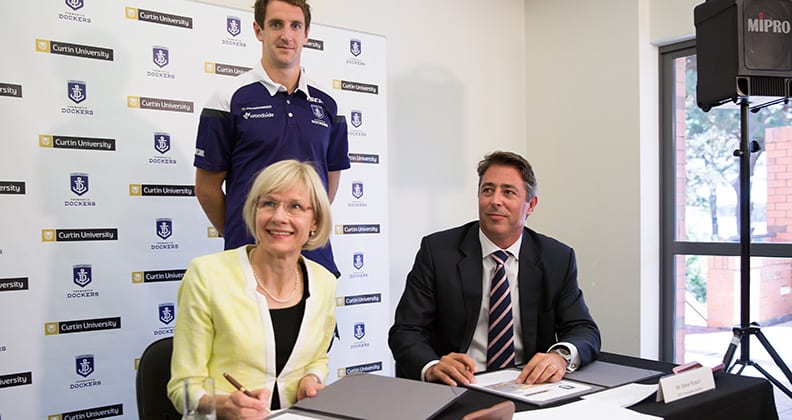 Vice-Chancellor Professor Deborah Terry, Fremantle Dockers player, Michael Barlow and Fremantle Dockers CEO Steve Rosich signing the agreement