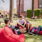 Group of students sitting on red bean bags at Henderson Court under the pine trees