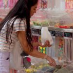 A female student filling a paper bag with lollies from the Curtin Student Guild G-Mart lolly wall