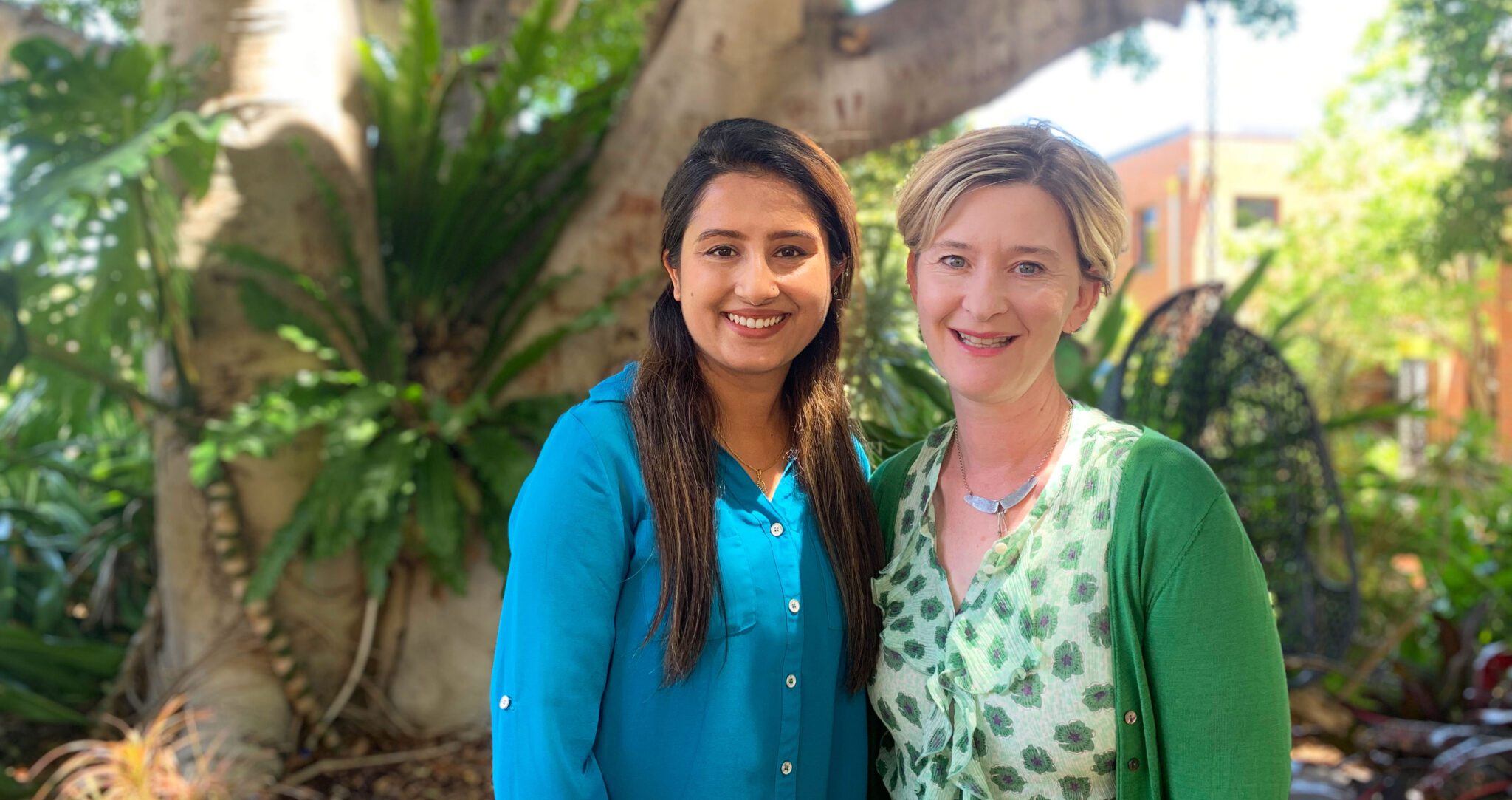 Anjali and Nina stand together and smile at the camera.