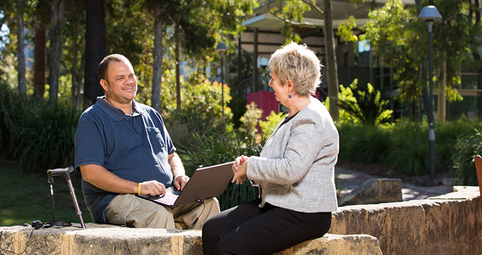 Student talking to AccessAbility staff member outdoors on campus