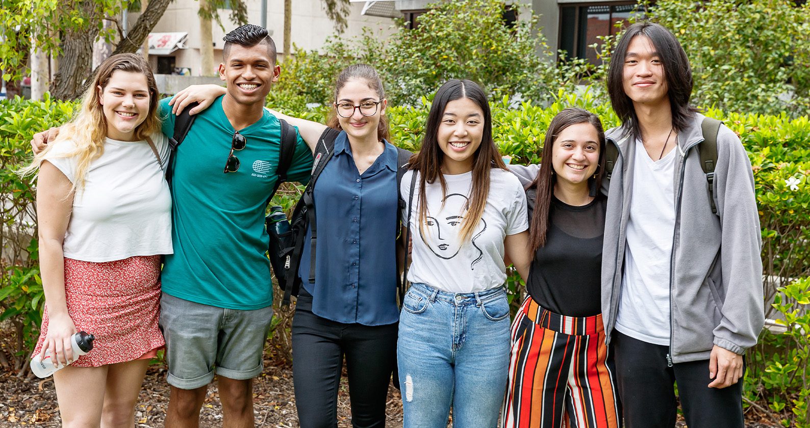 Six students standing arm-in-arm outdoors