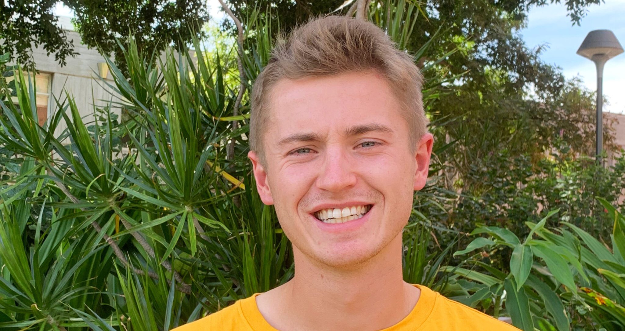 Jack smiles at the camera. He wears yellow.