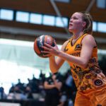 A female student on the Carnaby's basketball team preparing to throw a basketball.