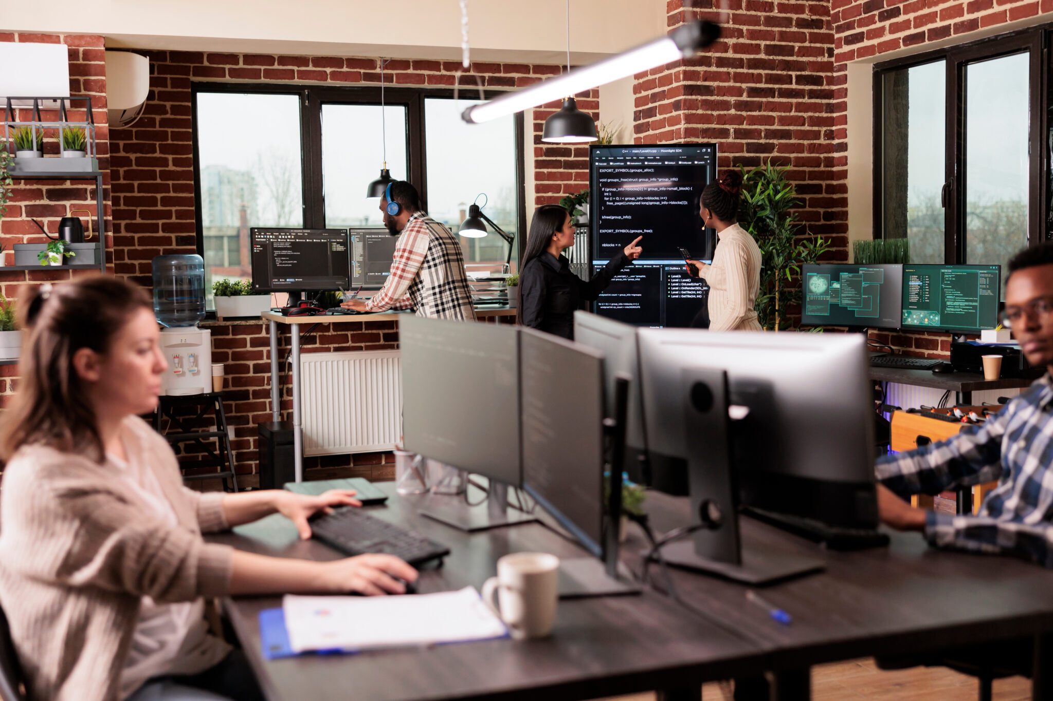 Team of programmers analyzing machine learning app code on programming big screen, standing in it company office. Software developers working on database system with html script
