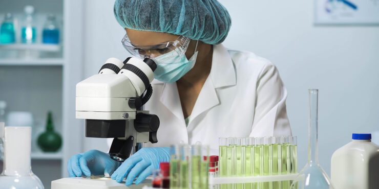 Woman scientist looking into microscope.