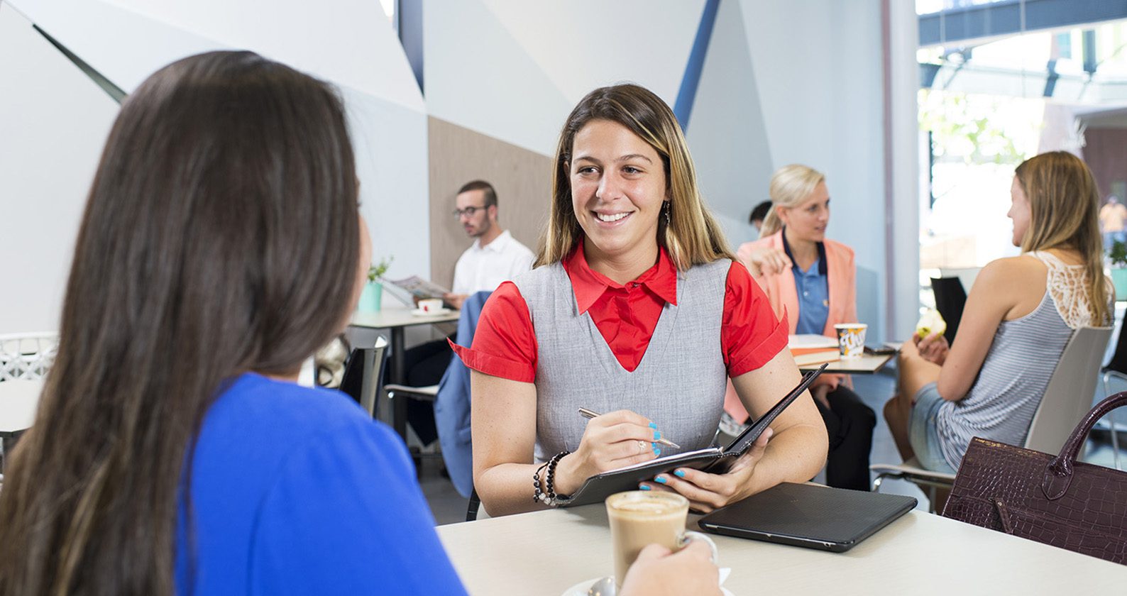 Two students in conversation sitting in a Cafe