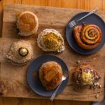 An aerial view of cinnamon scrolls and pastries displayed on a wooden serving board.