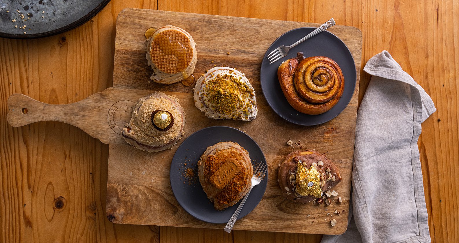 An aerial view of cinnamon scrolls and pastries displayed on a wooden serving board.