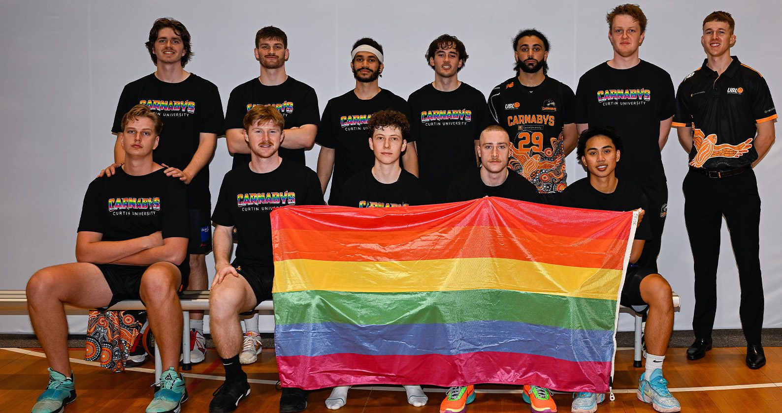 UBL men's team holding the Pride flag.