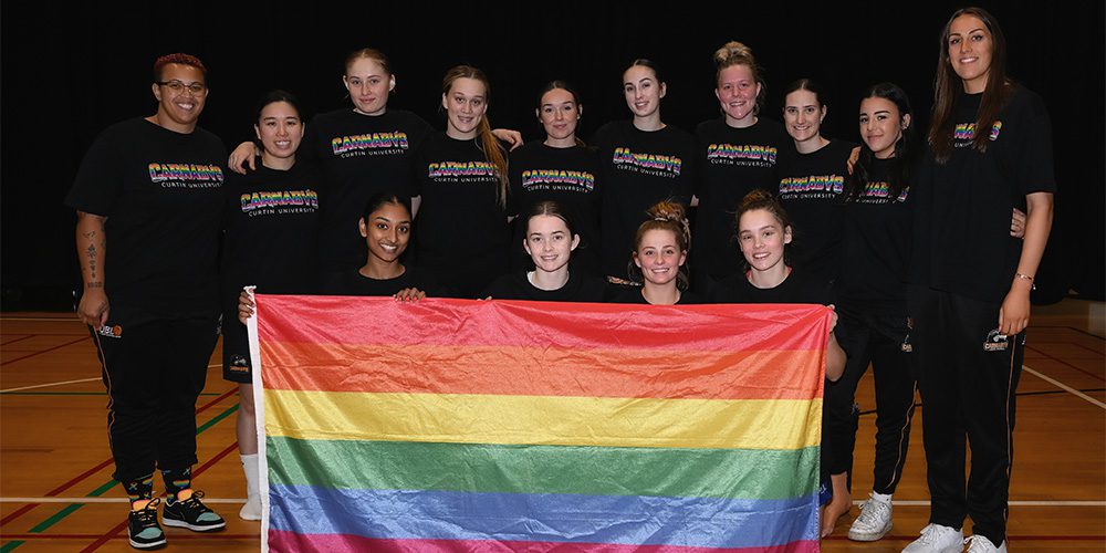 UBL women's team holding the Pride flag.