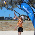 Student playing volleyball at a beach