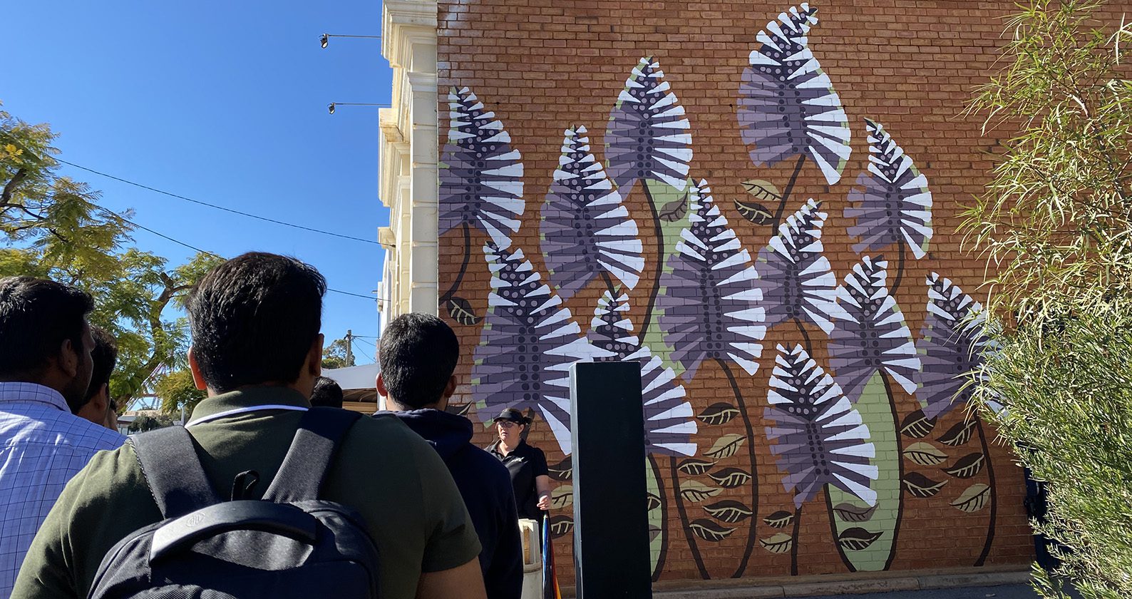 The new semester 2 2023 cohort in front of a colourful mural.