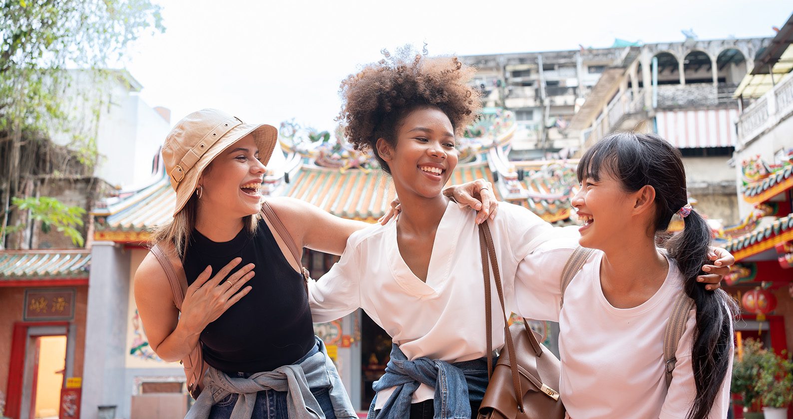 Three students stand together smiling outdoors.
