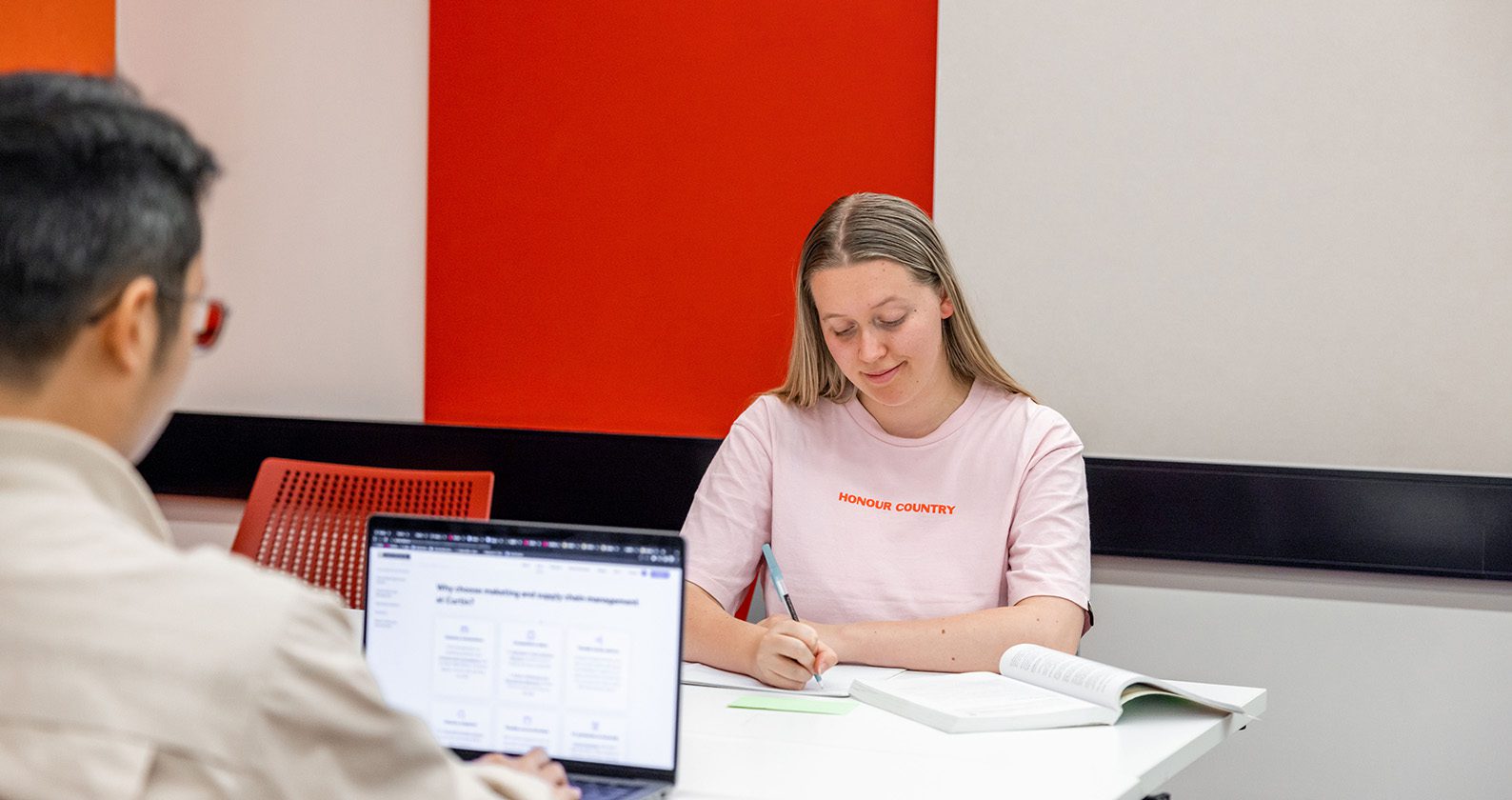 Two students sitting on a desk studying